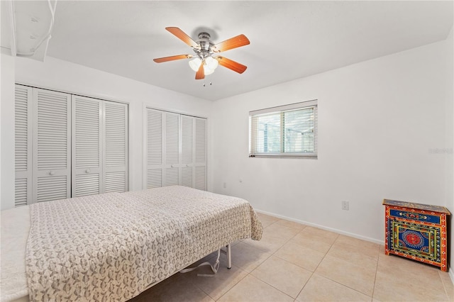 bedroom featuring ceiling fan, two closets, and light tile patterned floors