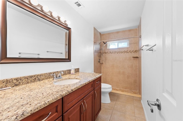 bathroom with vanity, tile patterned floors, toilet, and tiled shower