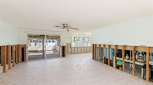 tiled empty room with ceiling fan and a textured ceiling