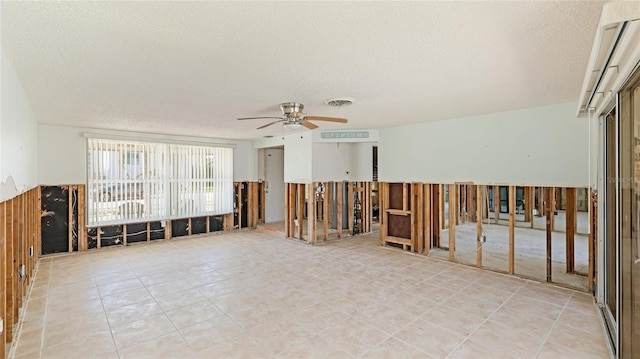 tiled empty room featuring ceiling fan and a textured ceiling