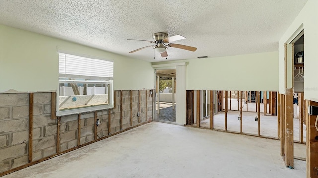 empty room with ceiling fan, concrete floors, and a textured ceiling