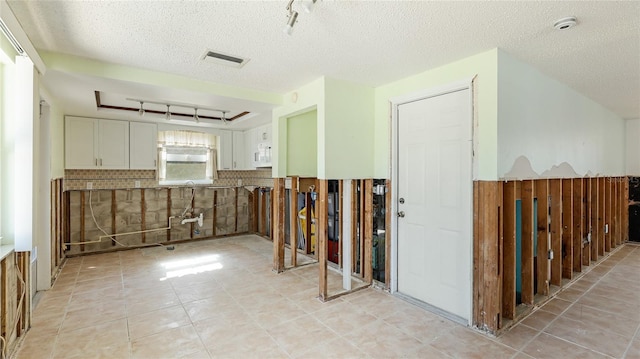 kitchen with white cabinetry, light tile patterned floors, and a textured ceiling