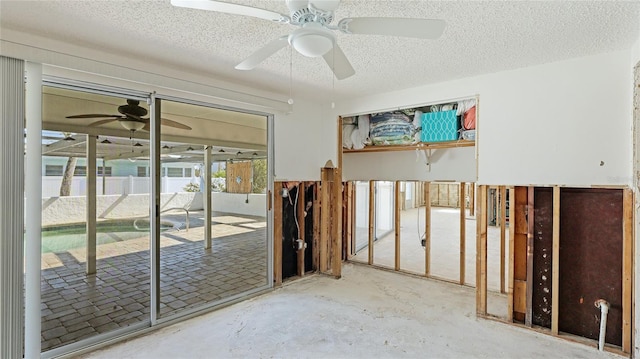 misc room featuring concrete flooring, ceiling fan, and a textured ceiling