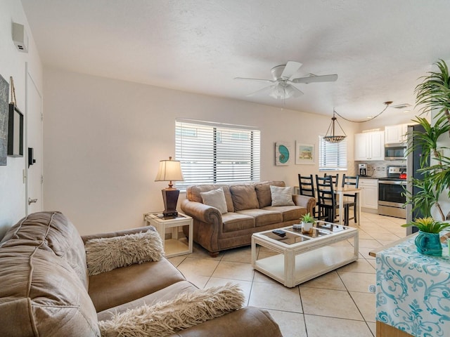 living room with light tile patterned flooring, ceiling fan, and a textured ceiling