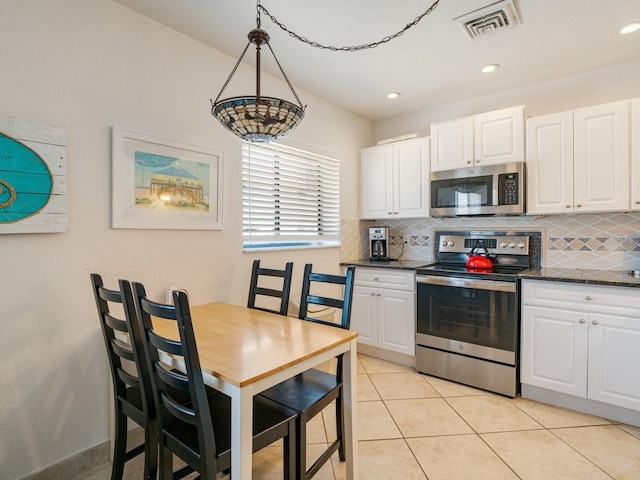 kitchen with pendant lighting, tasteful backsplash, white cabinets, and appliances with stainless steel finishes