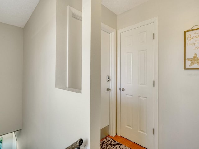 hallway featuring a textured ceiling and light hardwood / wood-style flooring