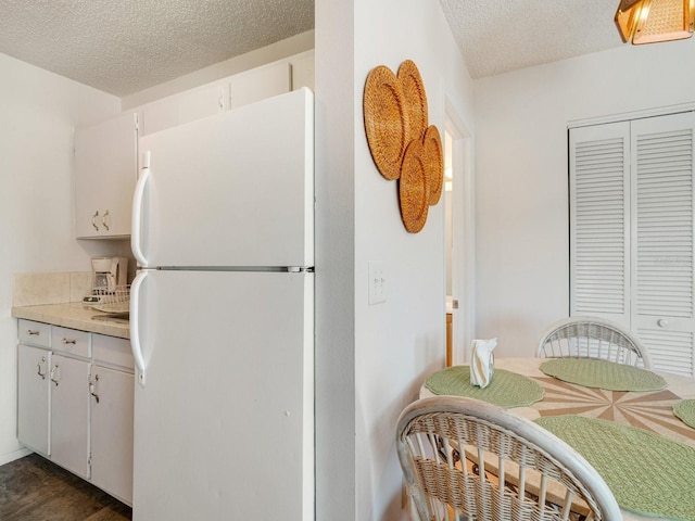 kitchen featuring white cabinetry, a textured ceiling, and white refrigerator