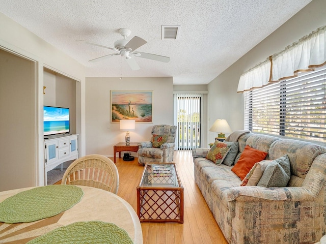 living room featuring lofted ceiling, a textured ceiling, ceiling fan, and light wood-type flooring