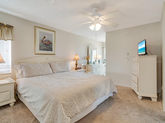 bedroom featuring ceiling fan, light colored carpet, and a textured ceiling