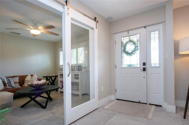 foyer entrance featuring light tile patterned floors, a barn door, and ceiling fan