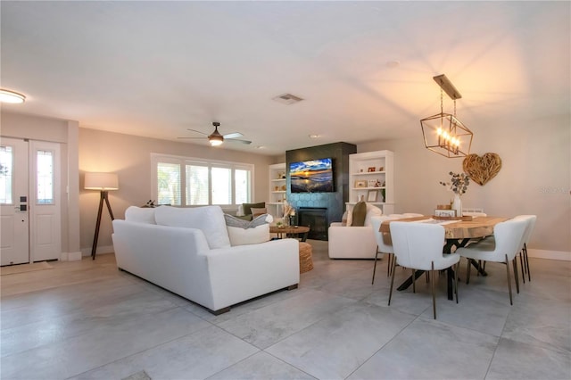 living room with a fireplace and ceiling fan with notable chandelier