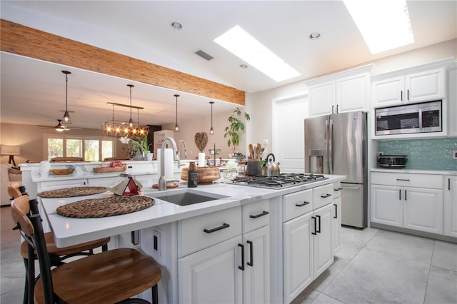 kitchen with appliances with stainless steel finishes, decorative light fixtures, sink, a breakfast bar area, and white cabinets