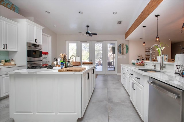 kitchen featuring pendant lighting, sink, stainless steel appliances, and an island with sink