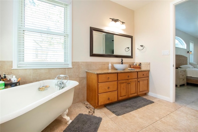 bathroom with vanity, a bathing tub, tile patterned flooring, and tile walls