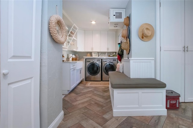 washroom featuring cabinets, light parquet floors, and washing machine and clothes dryer