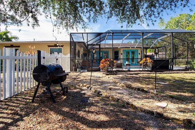 rear view of property featuring french doors and glass enclosure