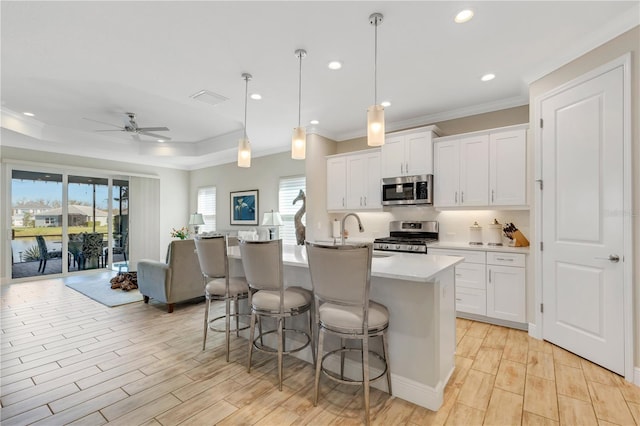 kitchen with stainless steel appliances, white cabinets, open floor plan, light countertops, and pendant lighting