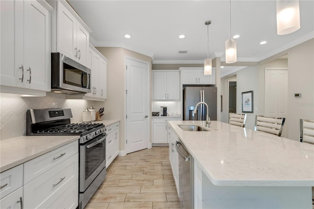 kitchen with stainless steel appliances, a kitchen island with sink, hanging light fixtures, and a sink