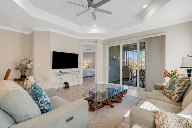 living area featuring light wood-style floors, a raised ceiling, crown molding, and baseboards