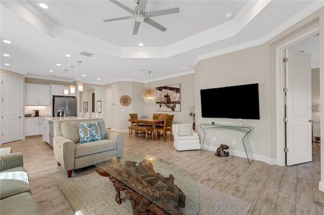 living room featuring baseboards, visible vents, a tray ceiling, crown molding, and light wood-type flooring