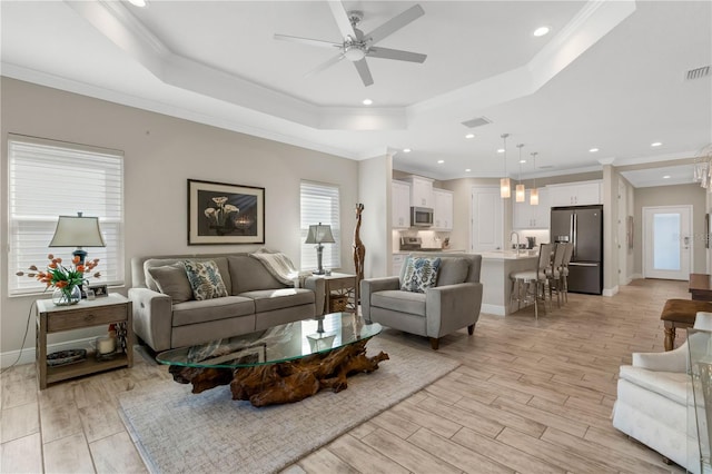 living room with light wood-style flooring, recessed lighting, baseboards, ornamental molding, and a raised ceiling