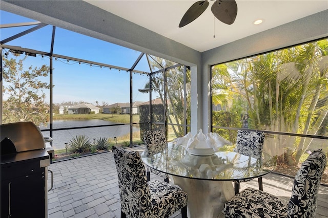 sunroom / solarium featuring a water view and a ceiling fan