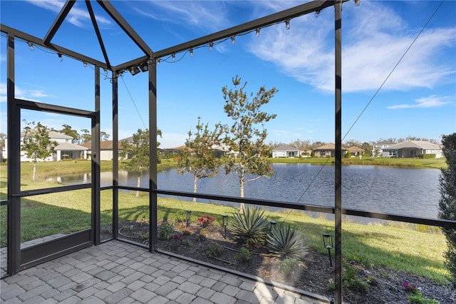 unfurnished sunroom featuring a water view and a residential view