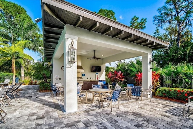 view of patio with a bar, area for grilling, fence, and a ceiling fan