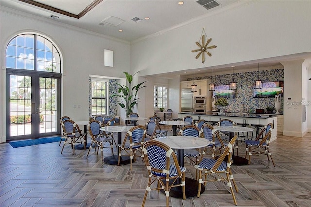 dining room with a towering ceiling, visible vents, and crown molding