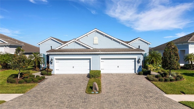 traditional home with a front yard, decorative driveway, an attached garage, and stucco siding