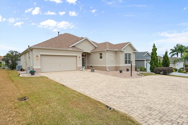 view of front facade with central AC unit, a garage, and a front yard