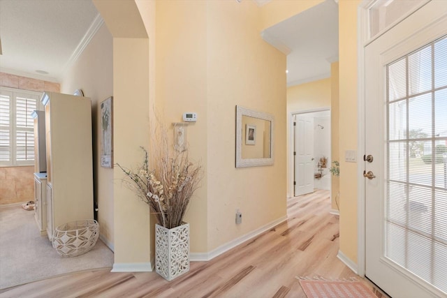 corridor featuring ornamental molding, plenty of natural light, and light hardwood / wood-style flooring