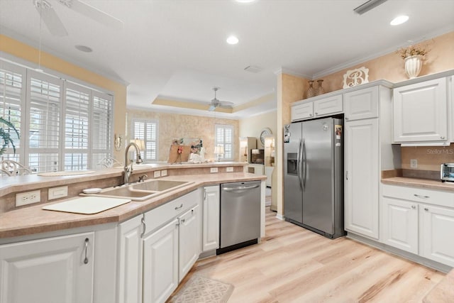 kitchen with appliances with stainless steel finishes, white cabinetry, sink, ceiling fan, and a tray ceiling