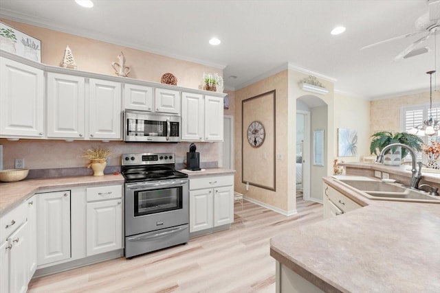 kitchen featuring appliances with stainless steel finishes, white cabinetry, sink, hanging light fixtures, and crown molding