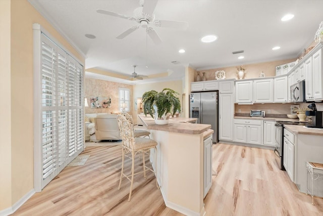 kitchen featuring crown molding, a kitchen breakfast bar, stainless steel appliances, light hardwood / wood-style floors, and white cabinets