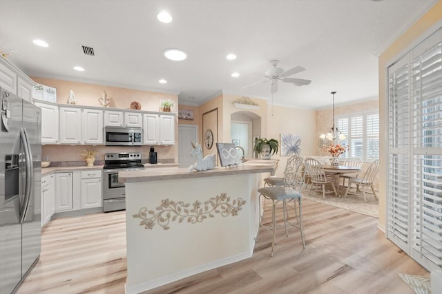 kitchen with stainless steel appliances, decorative light fixtures, an island with sink, and white cabinets