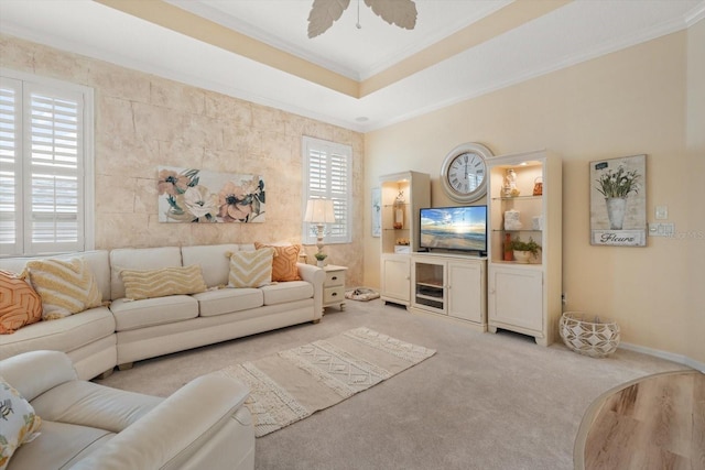 living room with a raised ceiling, ornamental molding, light colored carpet, and ceiling fan