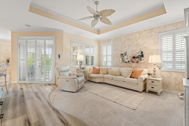 living room featuring crown molding, ceiling fan, a raised ceiling, and light hardwood / wood-style flooring