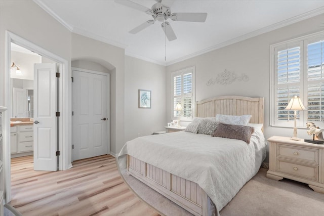 bedroom with crown molding, ensuite bath, light hardwood / wood-style floors, and ceiling fan