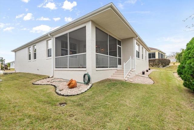 rear view of property featuring a lawn and a sunroom