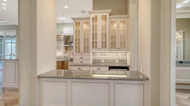 bar with stone counters, white cabinetry, and backsplash