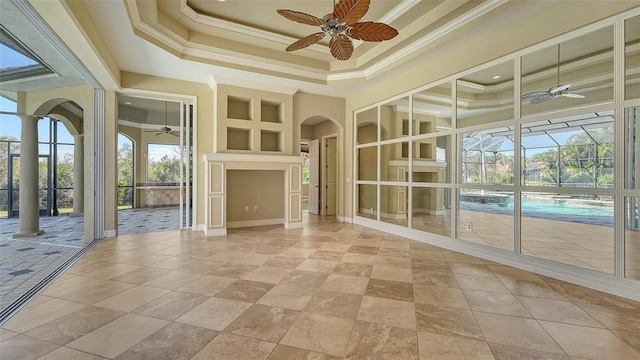 interior space featuring ceiling fan, a tray ceiling, and decorative columns