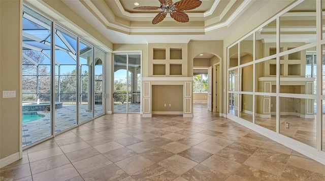 empty room featuring crown molding, a raised ceiling, ceiling fan, and a towering ceiling