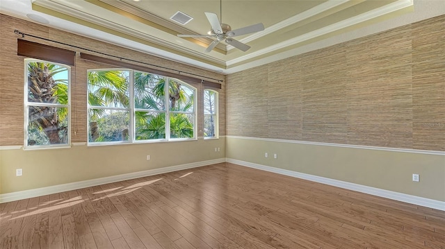 unfurnished room with hardwood / wood-style flooring, ceiling fan, ornamental molding, and a tray ceiling