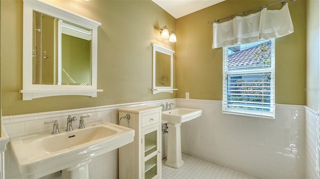 bathroom with double sink, tile patterned flooring, and tile walls