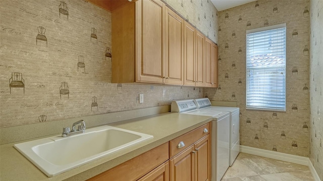 washroom with cabinets, washing machine and dryer, and sink