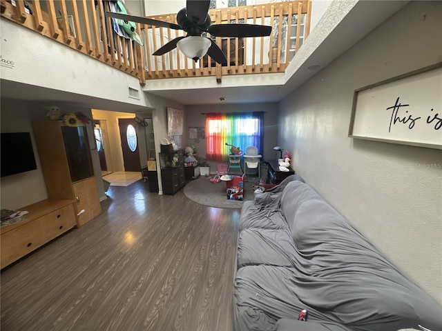 living room with hardwood / wood-style flooring, ceiling fan, and a high ceiling