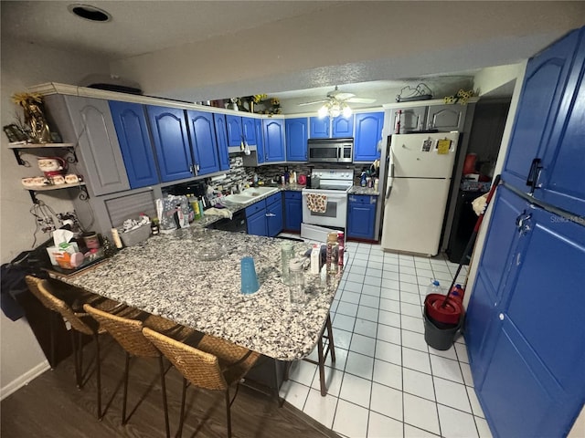 kitchen with light tile patterned flooring, blue cabinets, tasteful backsplash, ceiling fan, and white appliances