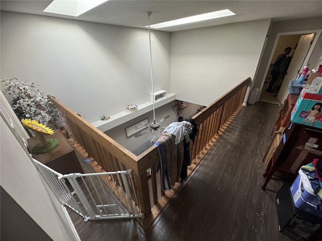 staircase with a textured ceiling, a skylight, and wood-type flooring