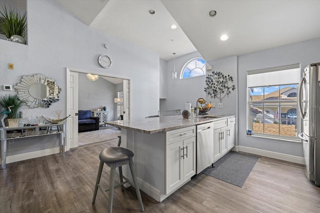 kitchen featuring appliances with stainless steel finishes, a breakfast bar, sink, white cabinets, and light stone countertops